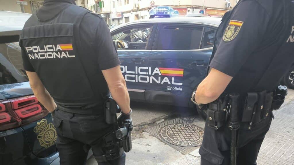 Heroin-Fund in Hotel auf Gran Canaria führt zu 4 Festnahmen Zwei Beamte der Nationalpolizei stehen im Einsatz neben einem Streifenwagen auf einer Straße.