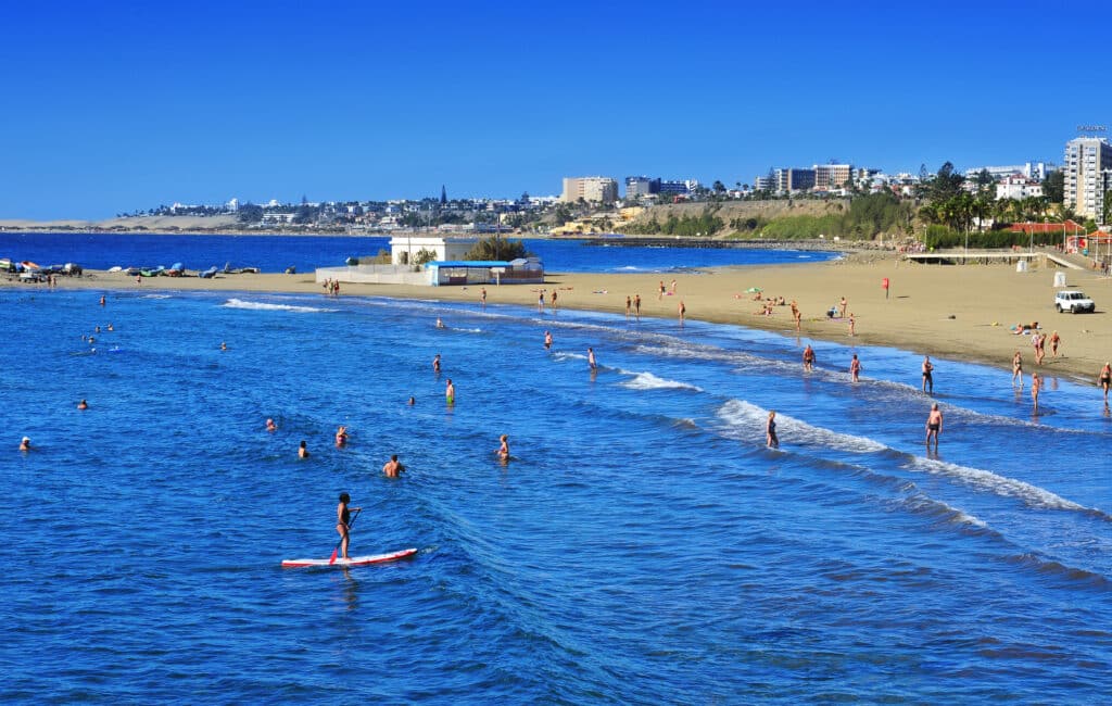 Der breite Sandstrand von Playa del Inglés auf Gran Canaria mit zahlreichen Badegästen am Meer.