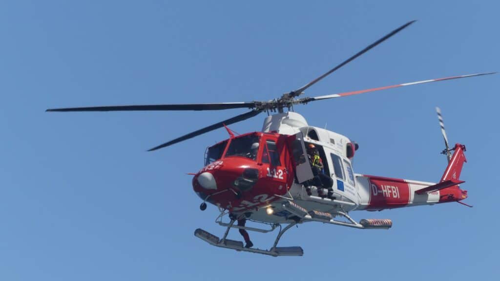 Strömung reißt Kind vor Las Palmas in den Tod Ein rot-weißer Rettungshubschrauber der kanarischen Notfallcrew fliegt bei einem Sucheinsatz im Tiefflug über dem Meer.